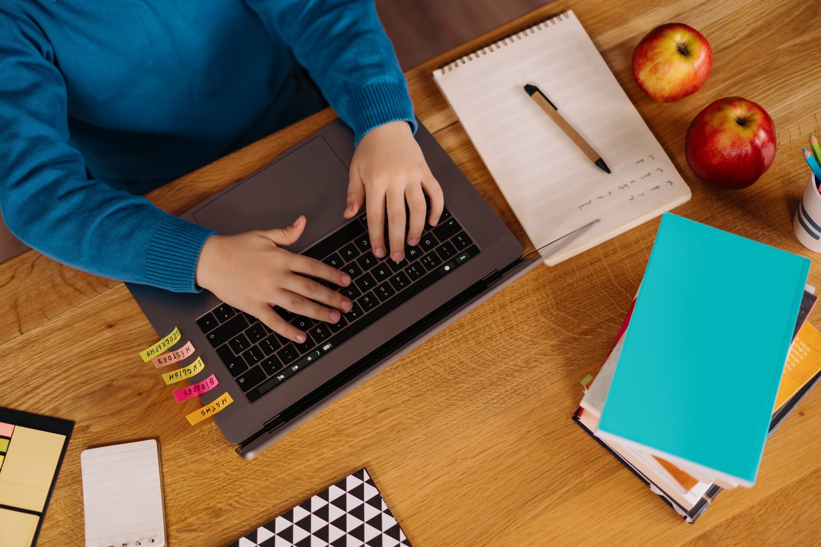 A Preteen boy uses a laptop to make online classes, top view , hands typing